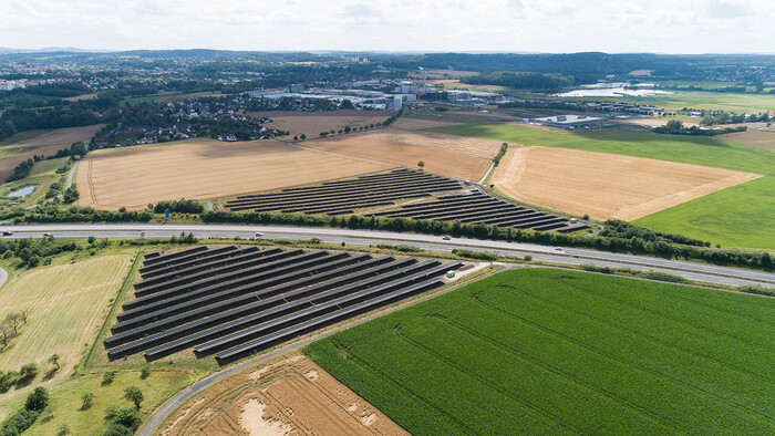 Grand parc photovoltaïque dans un paysage vallonné verdoyant – symbole de l'engagement en faveur d'une énergie respectueuse du climat et d'une alimentation durable en air comprimé.